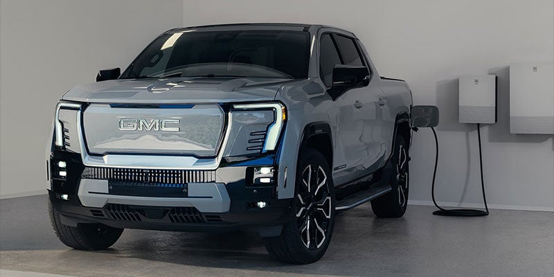 Photograph of a 2025 GMC Sierra EV Denali charging inside of a garage
